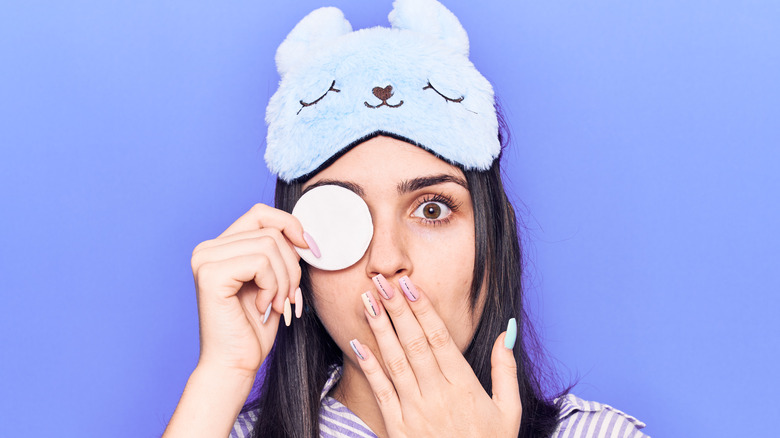 A shocked woman using makeup remover