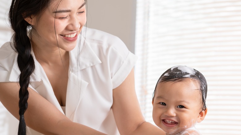 mom giving smiling baby a bath