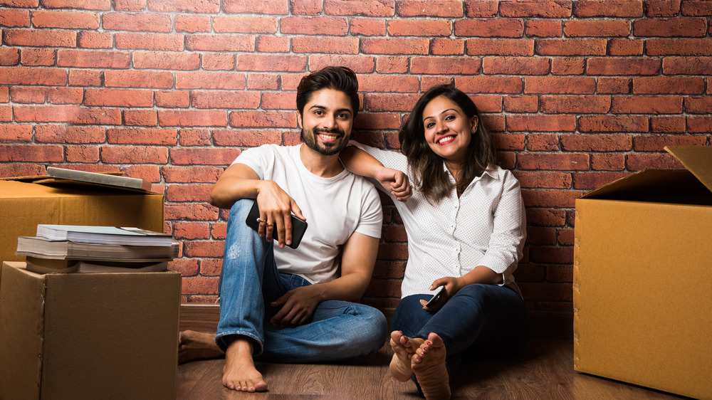 A couple sitting in front of an exposed brick wall among boxes 