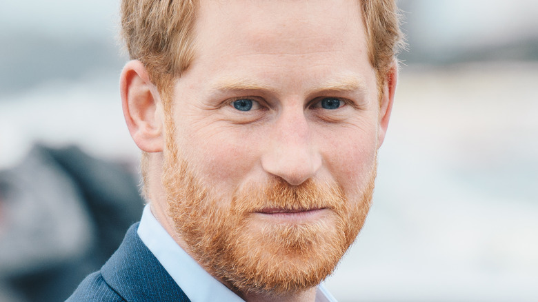 Prince Harry making a face surrounded by people