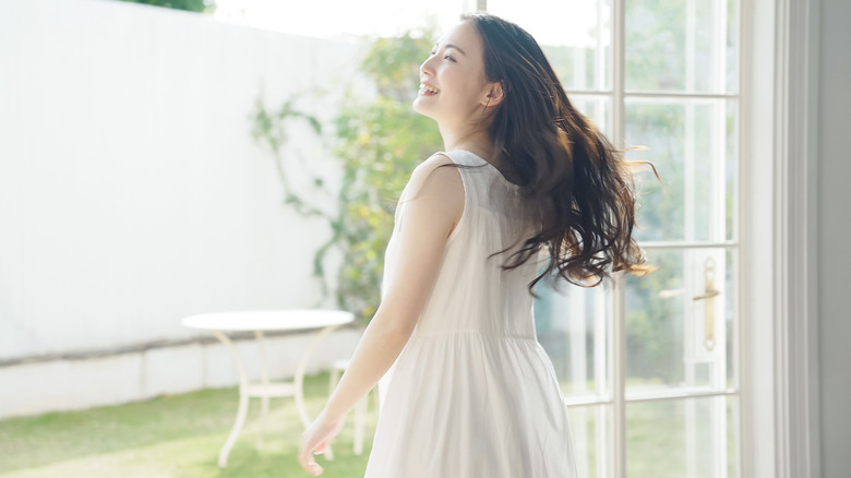 Woman smiling in sun at door