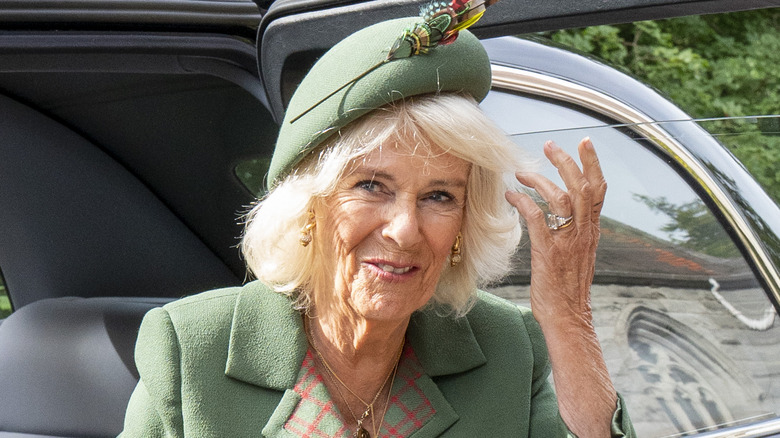 Queen Camilla smiling and adjusting her hair