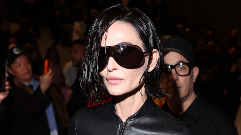 Demi Moore walking to her seat in oversized sunglasses at the Gucci FW26 show