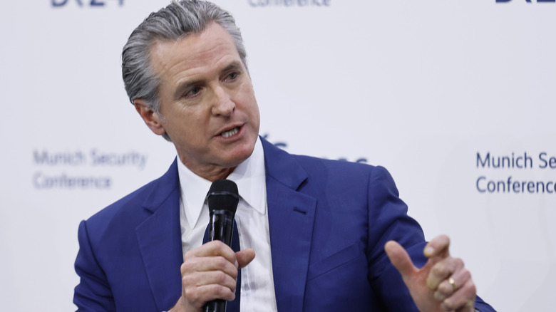 Gavin Newsom, in a white shirt and blue blazer, speaking at the Munich Security Conference