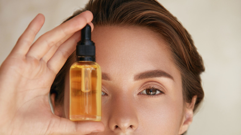 A woman holding a bottle of face oil