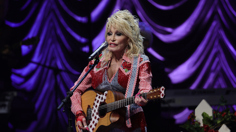 Dolly Parton performing on stage with a guitar
