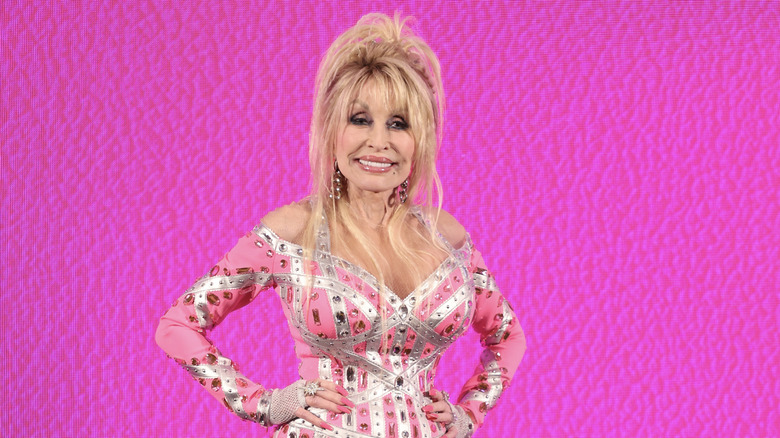 Dolly Parton posing against pink background