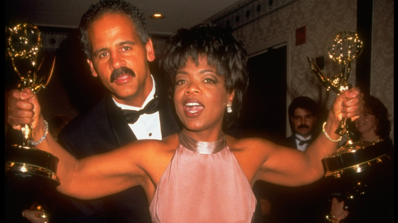 Stedman Graham hugging Oprah Winfrey, as she holds two Emmys