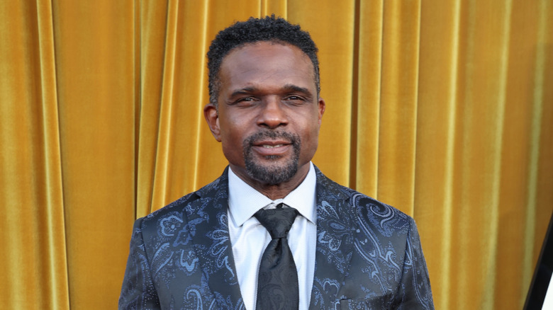 Darius McCrary posing for photos in a black suit with a white shirt