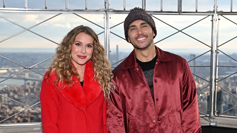 Alexa and Carlos PenaVega wearing red jackets atop the Empire State Building