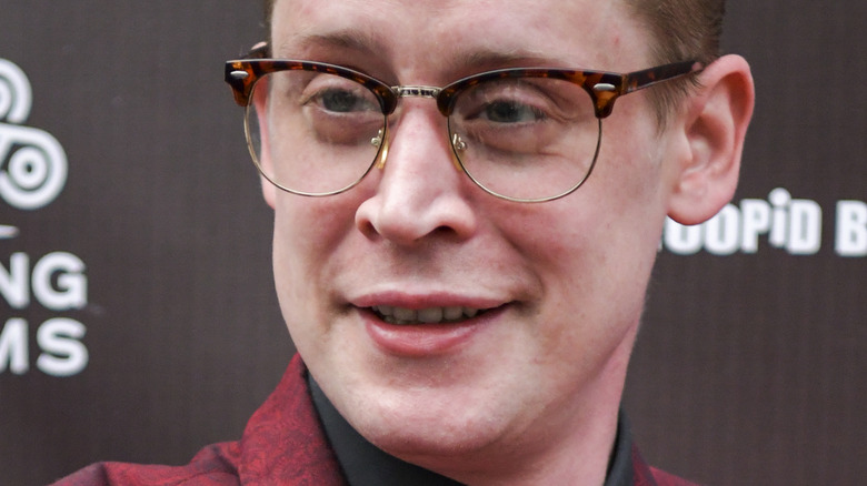 Macaulay Culkin wearing glasses on a red carpet