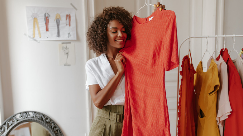 Woman picks out an orange dress from her wardrobe