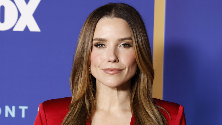 Sophia Bush posing at an event in a shiny red blazer