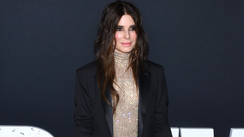 Sandra Bullock posing for photos in a black blazer and a sequined top