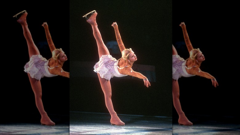 Nicole Bobek in white costume on one leg on the ice