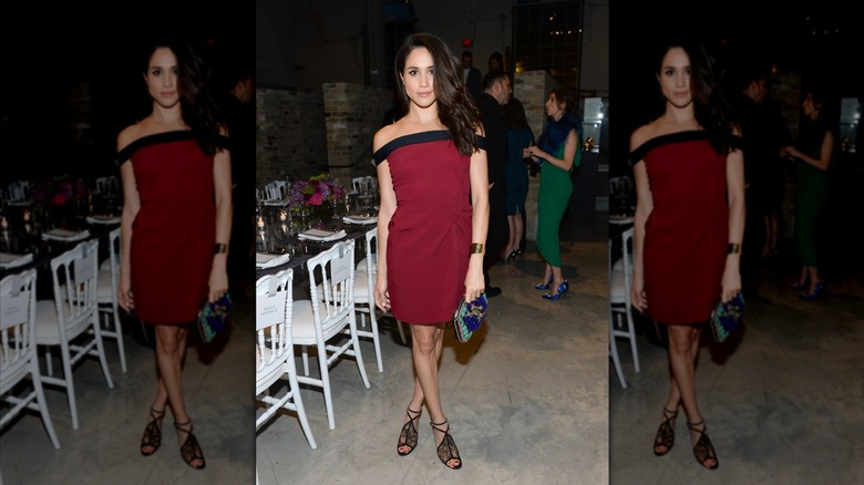Meghan Markle wearing a burgundy mini dress and holding an intricate blue clutch.