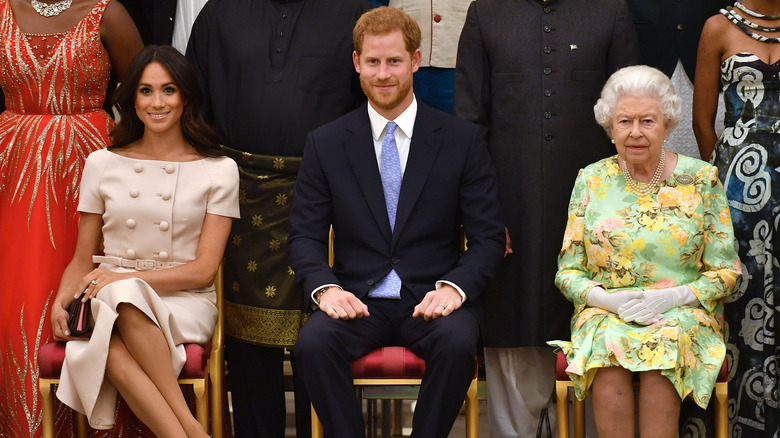 Meghan Markle seated next to Prince Harry and Queen Elizabeth II at a Buckingham Palace reception in 2018.