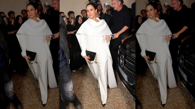 Meghan Markle wearing an all-white outfit with a with a white cape at Paris Fashion Week in 2025.