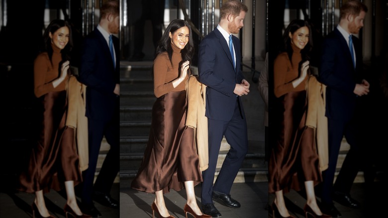 Meghan Markle wearing a brown monochrome outfit while walking next to Prince Harry during a visit to Canada House.