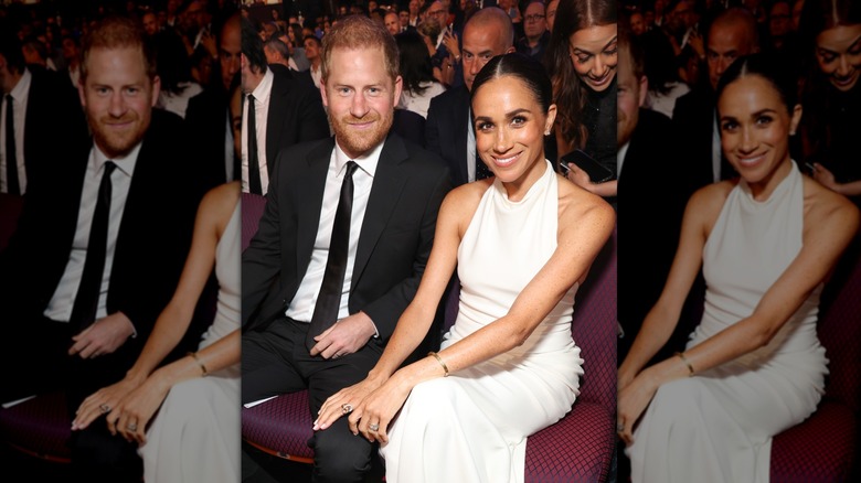Prince Harry wearing a black tuxedo and Meghan Markle seated next to him wearing a white gown at the ESPY Awards in 2024.