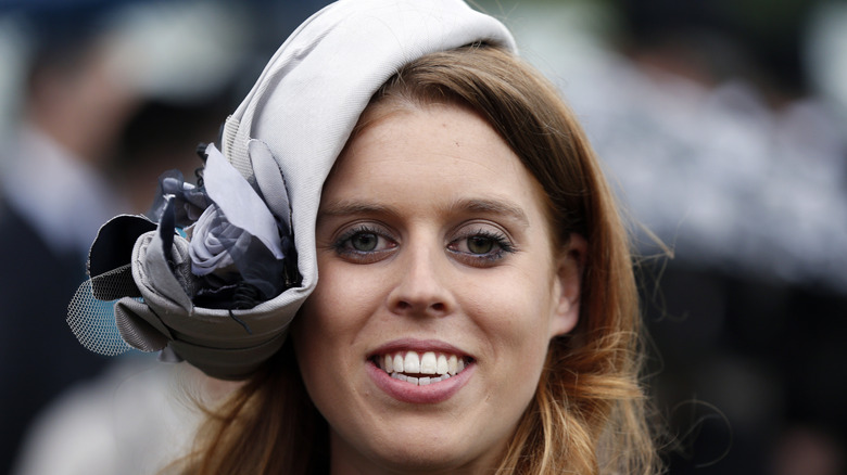 Princess Beatrice smiling in a gray fascinator
