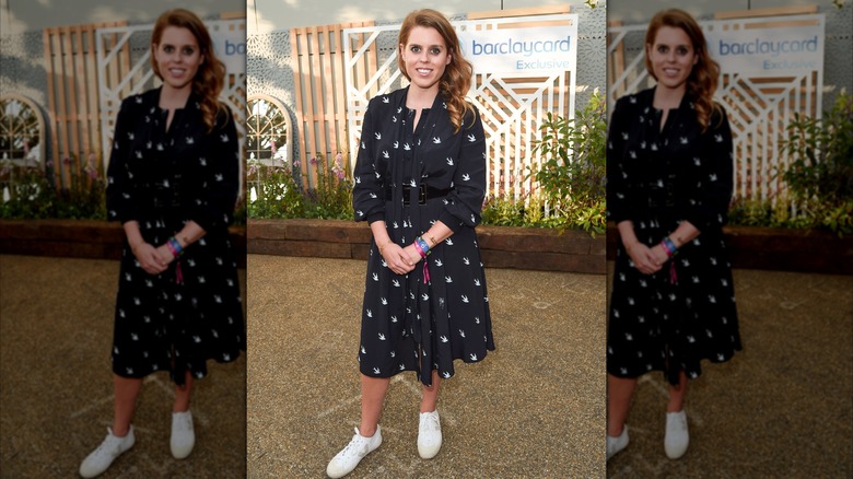 Princess Beatrice posing in a black dress with white sneakers