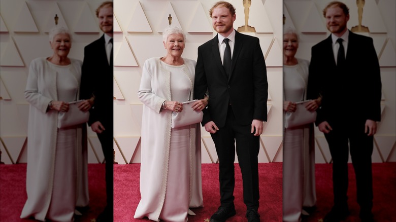 Judi Dench in a white dress standing next to Sam Williams in a suit at the 2022 Oscars