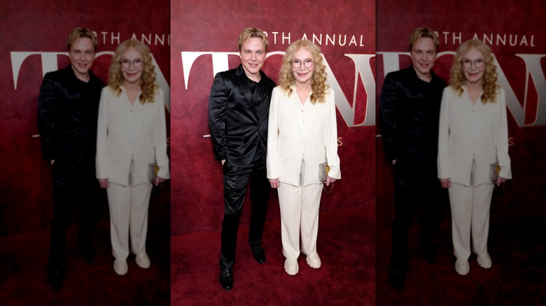 Ronan Farrow in a black pantsuit next to Mia Farrow in white pantsuit