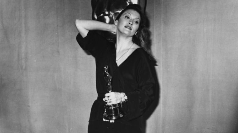 Faye Dunaway looking introspective as she holds her Oscar and puts her hand behind her head