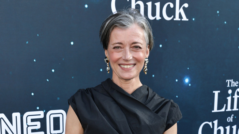 Mia Sara smiling while posing at an event in a black dress