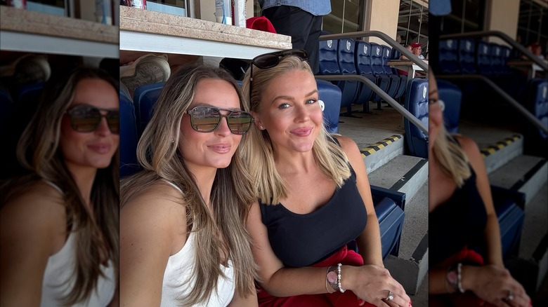 Karoline Leavitt smirking in a black sleeveless shirt next to Margo Martin who's wearing a white shirt.