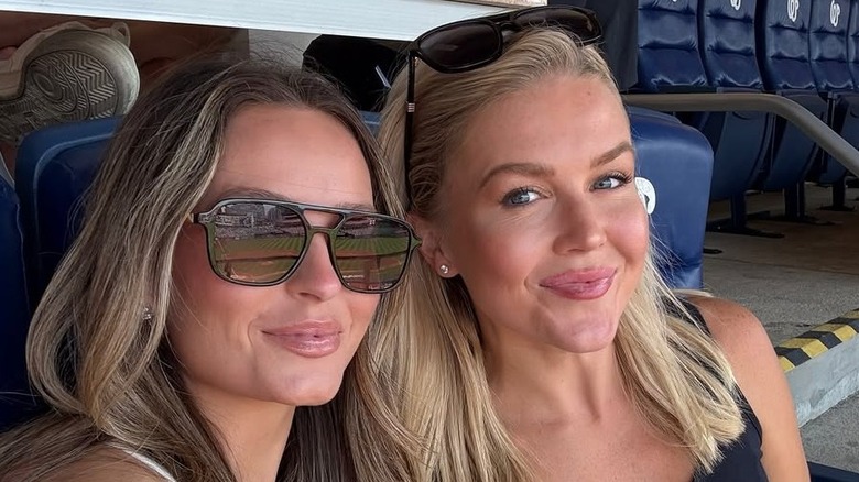Karoline Leavitt smirking in a black sleeveless shirt next to Margo Martin who's wearing a white shirt.