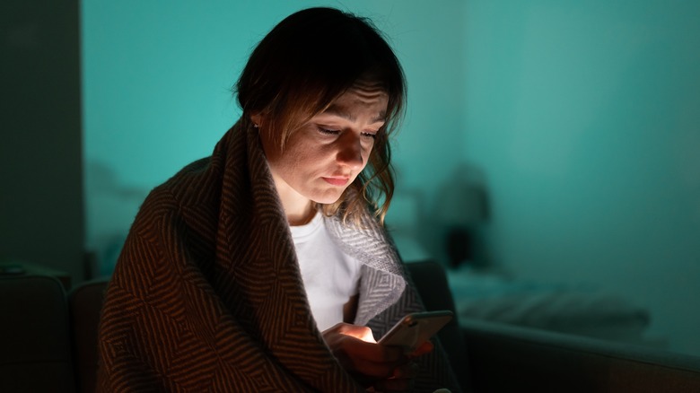 A woman scrolling through social media at night