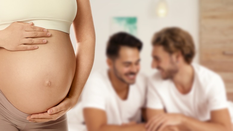 Pregnant woman and blurred view of happy couple