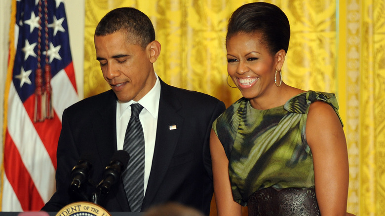 Michelle Obama smiling while Barack Obama talks in 2011