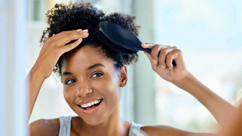 woman brushing hair with a paddle brush