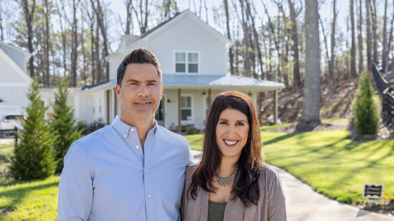 Ken and Anita Corsini posing in front of a house