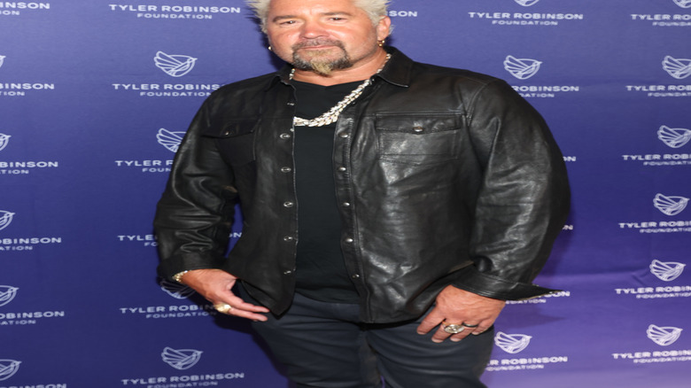 Guy Fieri posing in front of a blue background