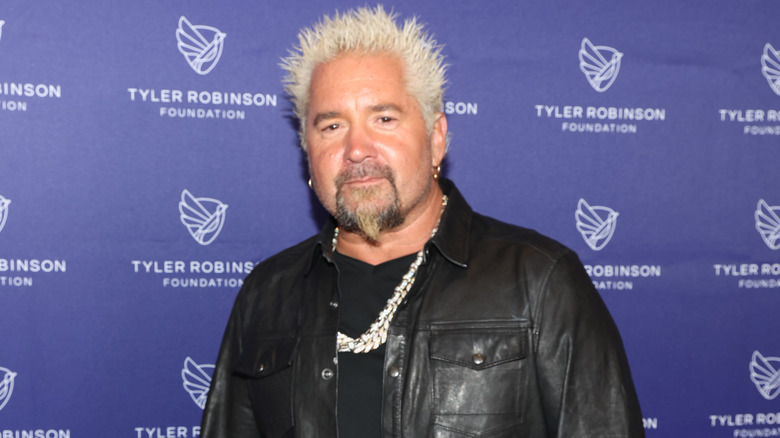 Guy Fieri posing in front of a blue background