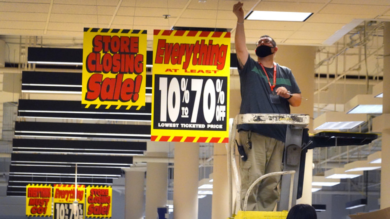 Sears employee hangs closing sign from the ceiling