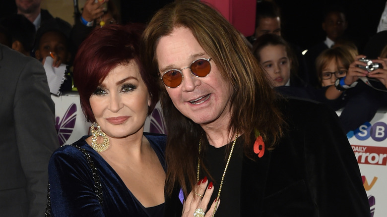Sharon Osbourne wearing a dark blue dress, Ozzy Osbourne wearing a black suit.