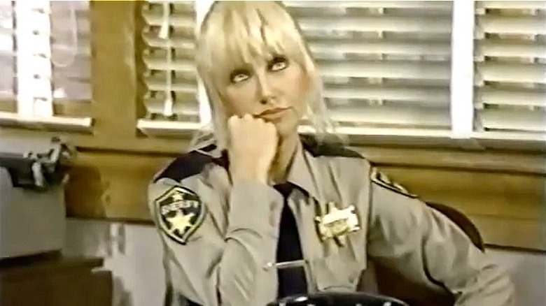 Suzanne Somers sits at desk in She's the Sheriff (1987)
