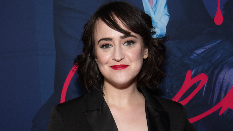Mara Wilson smiling while posing in a black outfit with red lipstick