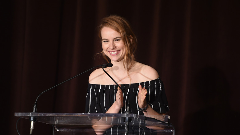 Bridgit Mendler smiling and clapping behind a podium