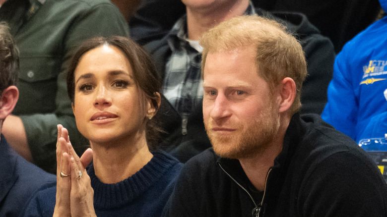 Meghan Markle and Prince Harry sitting together while Meghan claps.