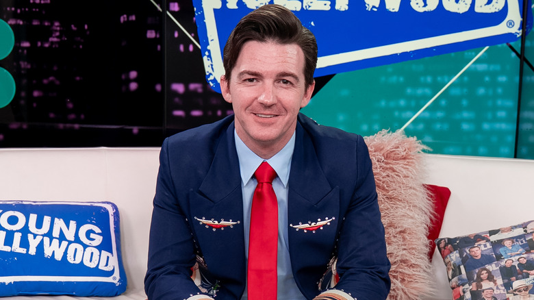 Drake Bell smiling while sitting on couch at Young Hollywood Studios