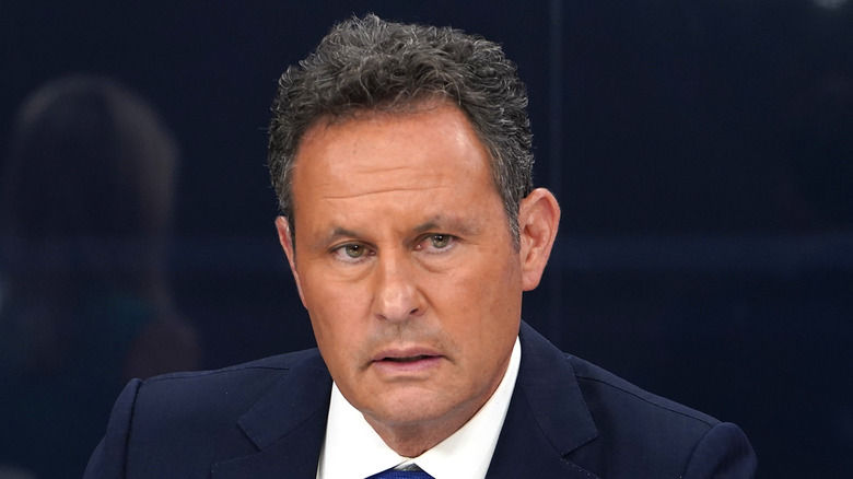 Brian Kilmeade sitting down wearing a suit and bright blue tie.