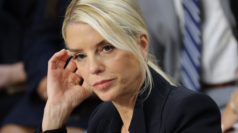 Pam Bondi pushing a piece of hair behind her ear at a hearing