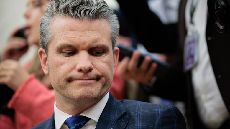 Pete Hegseth looking down while pursing his lips