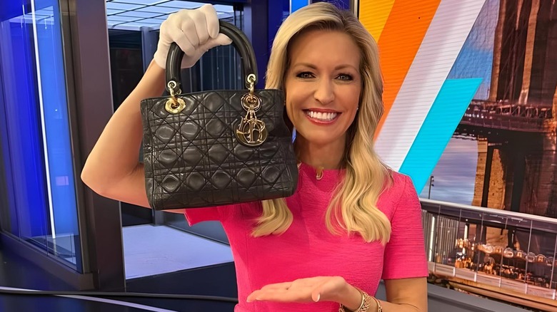 Ainsley Earhardt with over-bronzed face holding up a handbag